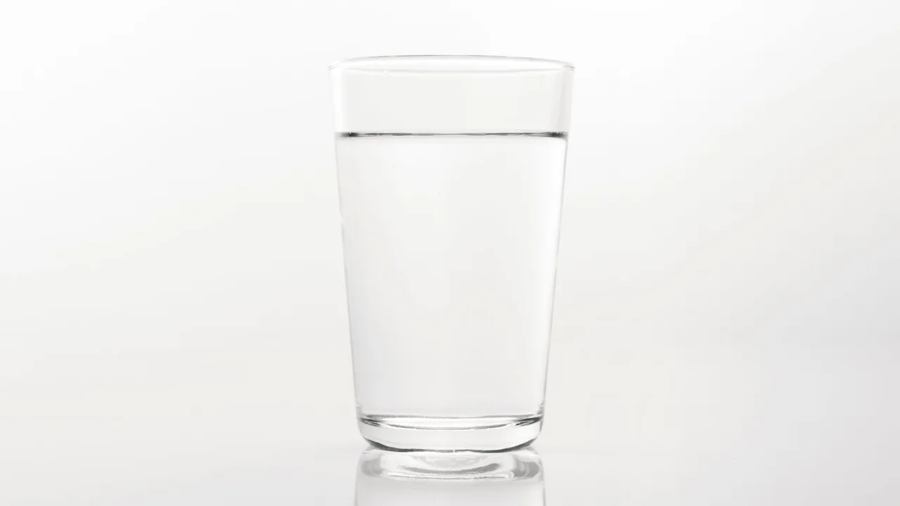 Verre d'eau posé sur une surface claire illustrant l'hydratation essentielle à la santé rénale