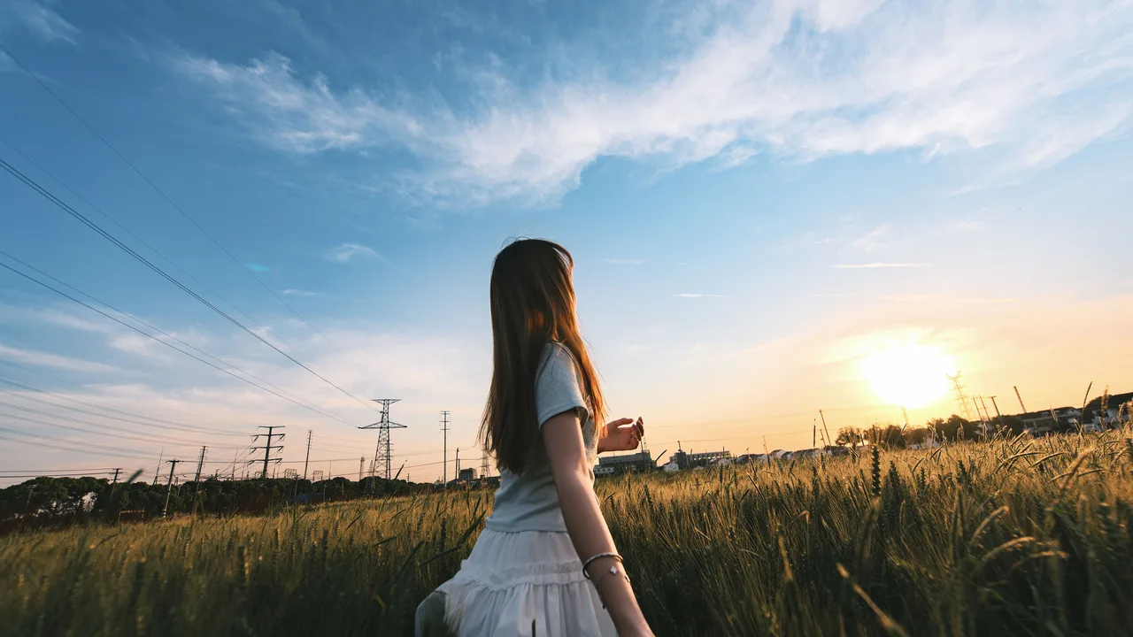 Femme debout dans un champ au lever du soleil, symbole de vitalité et d'énergie naturelle