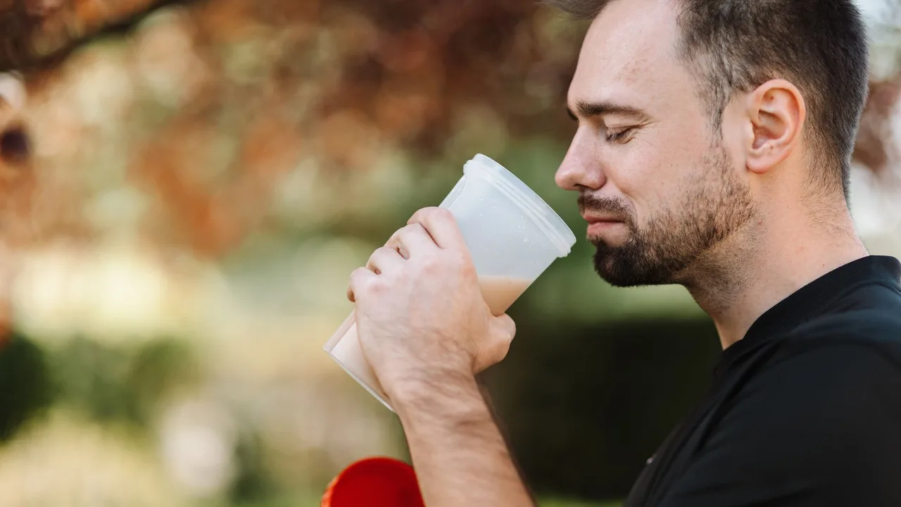 Homme tenant un shaker de protéines en extérieur illustrant la supplémentation en nutrition sportive