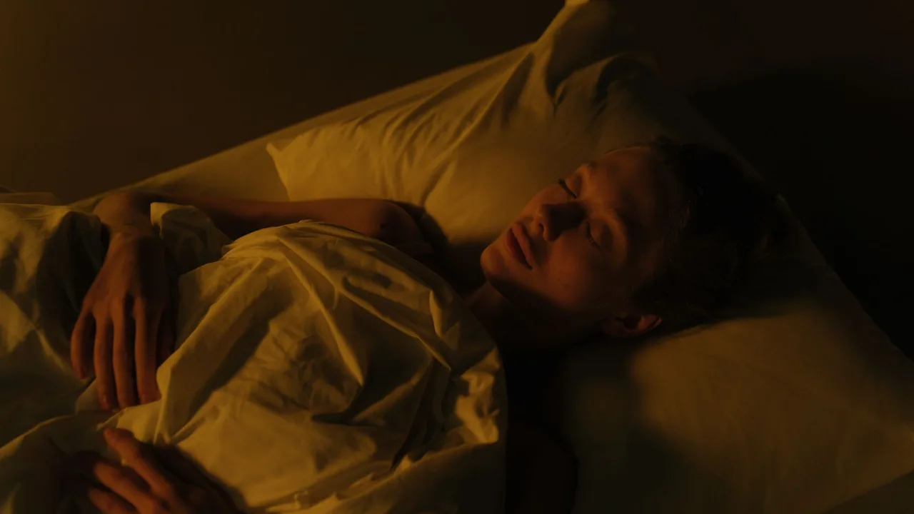 Femme dormant paisiblement dans une chambre tamisée, enveloppée dans une couverture blanche