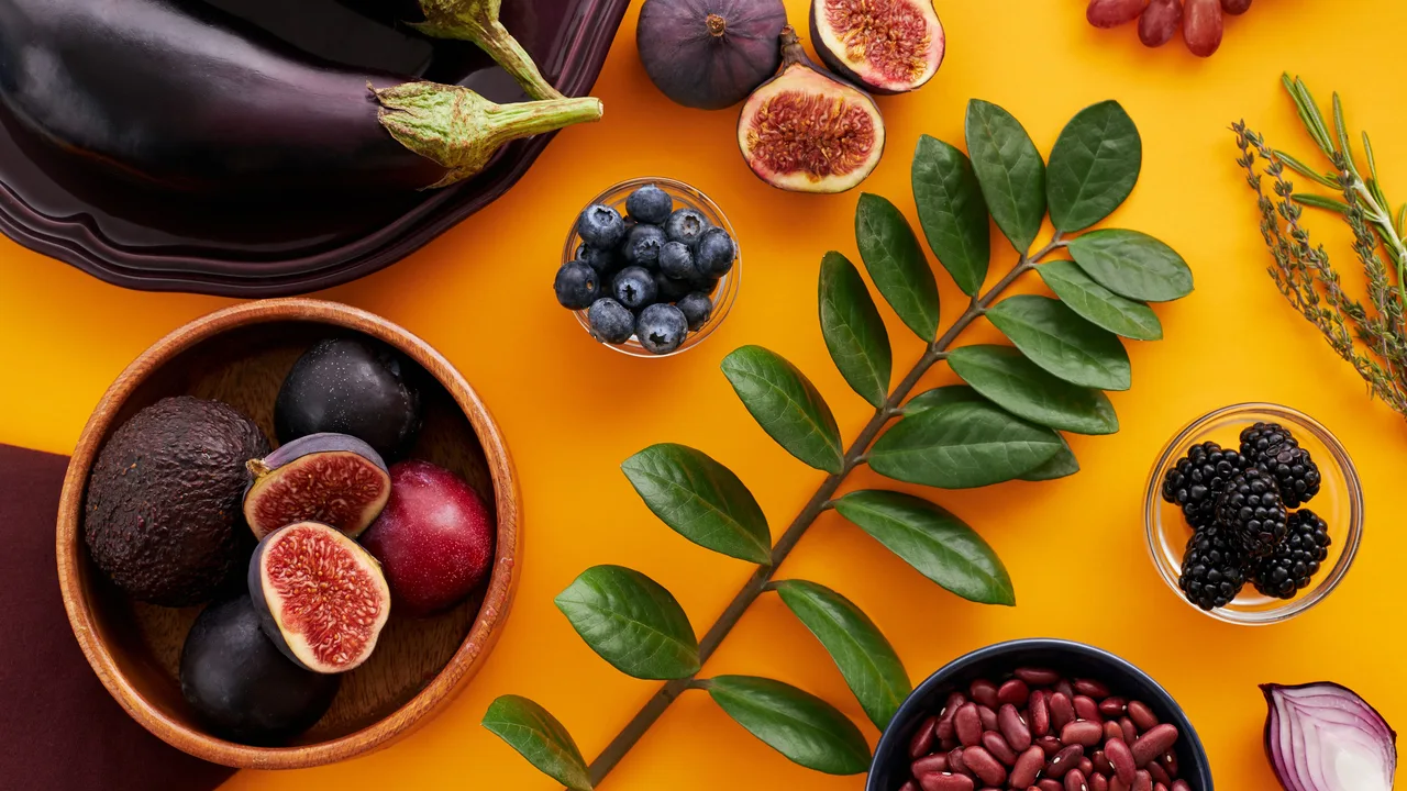 Assortiment coloré de fruits et légumes frais sur fond orange, symbolisant une alimentation à base de plantes