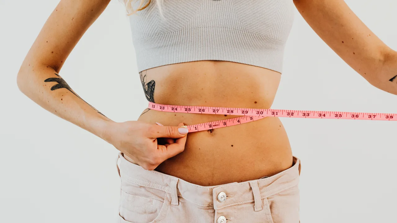 Femme mesurant son tour de taille avec un mètre ruban pour suivre sa composition corporelle